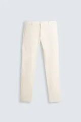 Pantalón chino de corte skinny fit color crema, confeccionado en tejido de mezcla de algodón y elasticidad. Cuenta con bolsillos frontales y traseros de vivo. El cierre es frontal con cremallera y botón.
