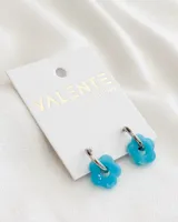 Aros de acero plateado con dije de flor celeste de acrílico.