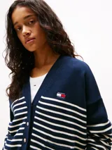 Cárdigan azul marino con rayas horizontales blancas, cuello en V, cierre frontal con botones dorados, dos bolsillos delanteros y logo de Tommy Jeans bordado en el pecho.