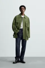 Parka verde militar de corte relaxed fit confeccionada en tejido técnico ligero. Cuello solapa y manga larga. Bolsillos de plastrón con solapa en delantero. Cintura ajustable en interior. Cierre frontal con cremallera oculta por solapa con botones a presión.