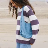 Bolso bandolera azul de tela con correa ancha ajustable y bolsillo externo.