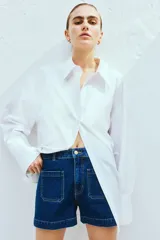 Short de denim azul de tiro alto con bolsillos delanteros y traseros. Cierre con botón y cremallera.