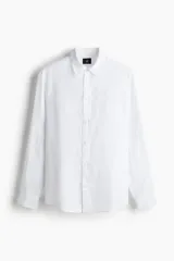 Camisa blanca de lino con cuello inglés, tapeta clásica y canesú en la espalda. Mangas largas con tapeta de manga y botón, y cierre ajustable de botón en los puños. Bajo redondeado. Corte estándar.