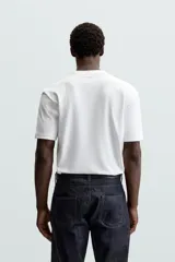 Camiseta blanca de algodón interlock con elasticidad, corte recto, cuello redondo y mangas cortas.