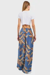 Pantalón ancho de tela estampada con hojas marrones sobre fondo celeste, con cintura elástica.