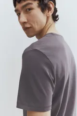 Remera gris de punto liviano con cuello redondo ribeteado y bajo recto. Corte ajustado que realza el contorno del cuerpo creando una silueta entallada. Confeccionada con tejido funcional COOLMAX®, una fibra exclusiva de poliéster de secado rápido que elimina la humedad y regula la temperatura corporal proporcionando un ajuste cómodo y suave.