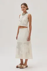 Falda midi color crudo, tejida de punto calado con diseño de flores. Cuenta con elástico y lurex en la cintura.