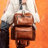 Mochila de cuero vacuno en colores tabaco y tostado, con dos bolsillos frontales y compartimento principal con cierre.