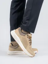 Zapatilla acordonada de cuero color beige con perforaciones en los laterales y suela blanca con base de goma color caramelo.