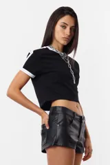 Remera corta negra de algodón tipo baby tee, con mangas cortas y detalles en blanco en cuello y mangas. Estampa frontal con la leyenda "Rocking Slaying" en blanco.