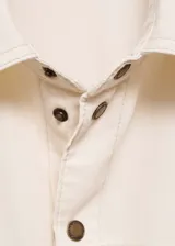 Camisa color crema de algodón estilo tejano vaquero, con cierre de cremallera y botón, cuello camisero, cinco bolsillos, manga larga y diseño oversize.