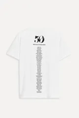 Camiseta blanca de algodón con cuello redondo y mangas cortas. Estampado fotográfico en blanco y negro con un grupo de personas y texto "Steven Meisel NYC February 12, 2025".