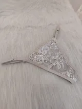 Microtanga de encaje color tostado con diseño floral y tiras ajustables.