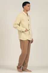 Campera color crema estilo sobre camisa hecha en lino premium con cuello clásico, cierre con botones marrones, dos bolsillos de parche inferiores y un bolsillo de parche superior.