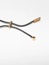 Collar con cordón negro ajustable y dos piezas de resina, una ovalada color ámbar y otra irregular color azul. Terminales dorados con logo grabado.