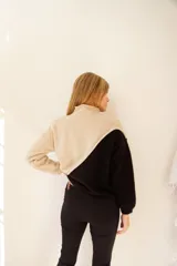 Sweater de punto color crema y mostaza, con cuello cisne y diseño asimétrico.