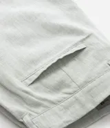 Bermuda de hombre en lino color gris claro, de corte recto, con textura discreta, bolsillos laterales y cierre frontal con botón y cremallera.