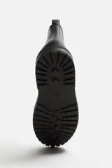 Bota Chelsea de cuero negro con elásticos laterales, tirador trasero y suela track.
