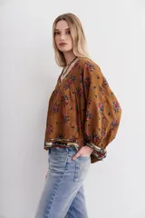 Camisa marrón con estampado floral y lentejuelas, escote en V y mangas largas abullonadas.