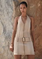 Vestido corto color beige, con cuello halter, cierre frontal con cremallera y cinturón con hebilla.