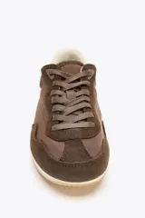Zapatillas deportivas marrones con detalles en gamuza y talón en blanco. Cierre con cordones y suela de goma color hueso.