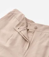 Pantalón de corte ancho confeccionado en sastrería de viscosa color beige, con cintura alta, trabillas, cierre con botón forrado y bolsillos laterales.
