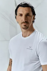 Remera deportiva blanca de manga corta y cuello redondo, con logo de la marca Zlatan en el pecho. Corte ajustado.