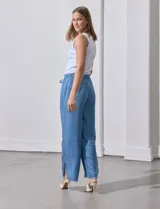 Pantalón celeste de lyocell, corte ancho, con cintura elastizada ajustable con cordón y ruedo desflecado con tajos laterales.