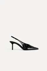 Zapato destalonado de cuero negro con punta fina, tacón fino y detalle de ojales metálicos.