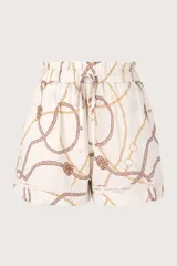 Short de tiro alto color blanco marfil con pretina fruncida ajustable con lazo. Presenta un estampado náutico de cuerdas y cadenas en tonos marrón y dorado. El ruedo tiene un detalle de tira bordada blanca.