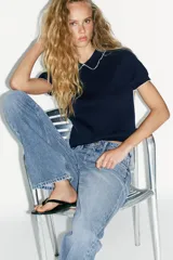 Top azul marino de punto con cuello solapa y manga corta. Detalle de acabados con vivos blancos a contraste en cuello y mangas.