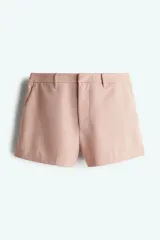 Short de vestir color rosa pálido, de corte recto, con bolsillos laterales y traseros. Se ajusta a la cintura con botón y cierre oculto.