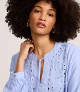 Blusa tipo bata de mangas largas, color celeste, confeccionada en viscosa, con cuello padre con lazo y botones, bordado floral en el busto.