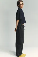 Zapatillas deportivas amarillas con detalles en negro y blanco. Presentan una combinación de materiales y texturas en el cuerpo, tirador en la lengüeta y cierre mediante cordones.