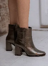 Bota corta color peltre de cuero, con taco geométrico y punta cuadrada. Presenta detalle de tachas pequeñas en el lateral y cierre con cremallera.