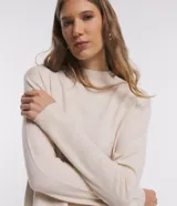 Blusa de punto color crema, con cuello alto y mangas largas.