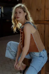 Musculosa marrón de gamuza con bordados blancos en el frente y detalle de flecos en los hombros. Tiene cuello redondo y sisas amplias con terminación de crochet.