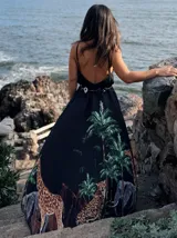 Vestido largo negro con estampado de jungla con palmeras, jirafas y leopardos. Tiene breteles finos, escote en V cruzado y cinturón con apliques brillantes.