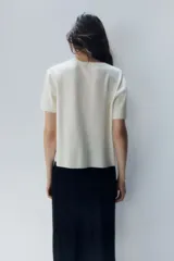 Remera color crudo de punto fino, con cuello redondo y mangas cortas.