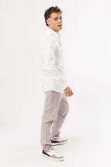 Camisa blanca de corte slim fit, manga larga y cuello clásico. Cierre frontal con botones.