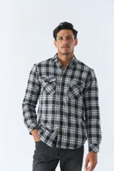 Sobrecamisa de algodón para hombre con interior de corderito, estampado a cuadros en tonos negro, blanco y azul. Tiene cierre de botones, bolsillos tipo cartera y logo en goma. El modelo usa talle M.