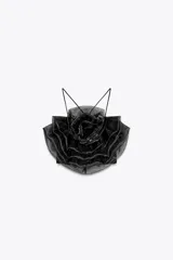 Top negro de organza con cuello halter, tirantes finos y detalle de maxi flor con volumen.