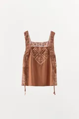 Top marrón con escote cuadrado, tirantes anchos y detalle de puntilla y bordados en forma de rombos. Aberturas laterales ajustables con lazadas.