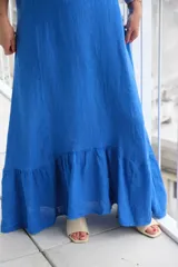 Vestido largo sin mangas, color azul francia, con escote redondo y bolsillos laterales. Presenta un volado en el ruedo que aporta movimiento.