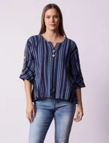 Blusa de algodón con estampado a rayas verticales en tonos celeste, rosa y blanco. Tiene cuello redondo con escote en V y abertura con botones de madera. Las mangas son 3/4 con aplique de botones.