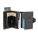 Billetera compacta de cuero sintético color gris oscuro, con cierre vertical plateado en el frente y un bolsillo exterior con broche a presión.