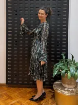Vestido midi negro con estampado floral, mangas largas y cuello con volantes plisados.