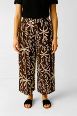 Pantalón ancho de tiro alto, color marrón oscuro con estampado botánico en beige claro, con cintura elástica.