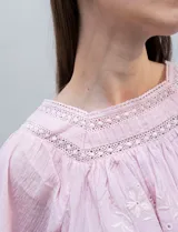 Blusa rosa claro de algodón con escote cuadrado, manga larga y bordado floral en el frente y las mangas.
