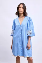 Vestido blanco de lino con escote en V, mangas cortas abullonadas y bordados florales en beige en mangas y ruedo.